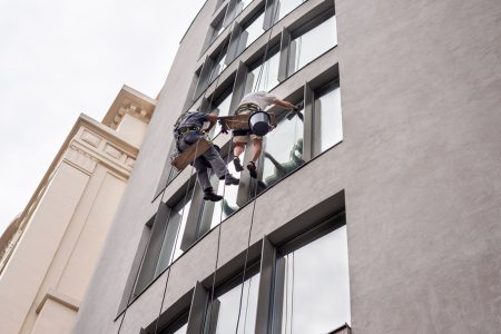 dos-trabajadores-lavando-ventanas-fuera-edificio